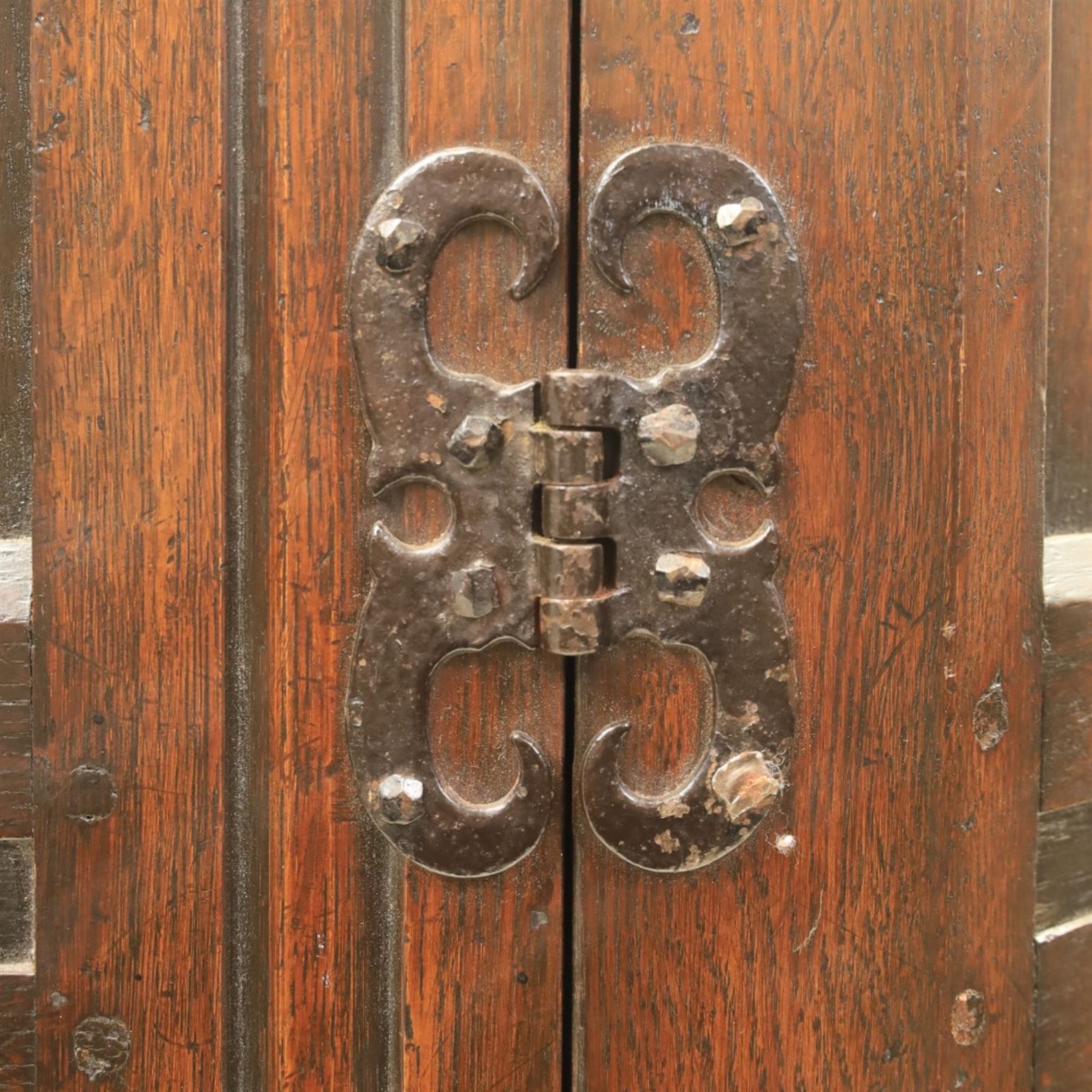 20th century dark stained oak hall robe, cantered sides enclosing a hooks and a shelf, panelled and carved sides, raised on stile supports