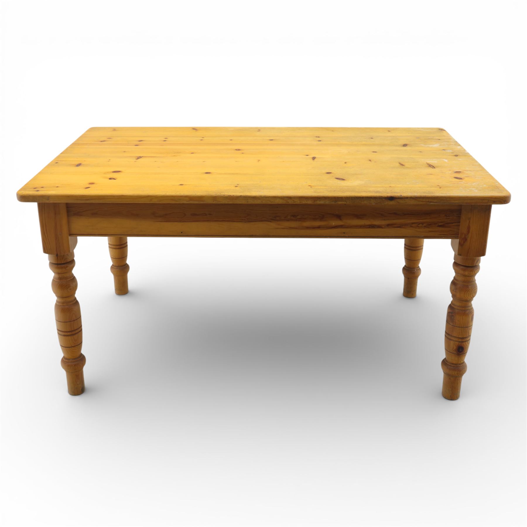 Late 20th century pine farmhouse dining table and four chairs, the rectangular plank top with rounded corners over two frieze drawers fitted with turned knob handles, raised on turned legs, the chairs with shaped ladder backs and turned finials, rush seats in a herringbone weave, on turned supports united by stretchers