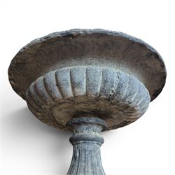 Pair of cast stone garden urns of kylix form on pedestals, the broad egg-and-dart moulded rim over a shallow gadrooned underbelly, with waisted tapering base, raised on matching plinth bases with faux panelled facia