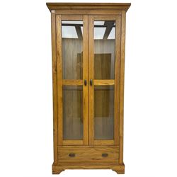 Tall oak display cabinet, projecting cavetto cornice over two glazed doors and single drawer, on bracket feet