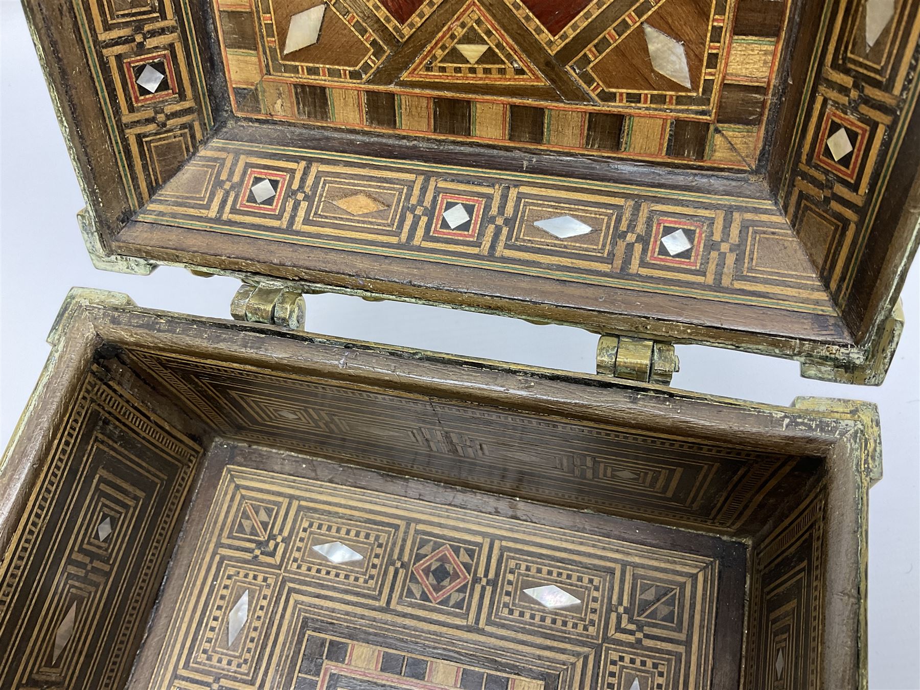 Late 19th century Damascus Cairoware Quran box, of square form with canted hinged cover, upon four circular pad feet, the brass exterior inlaid with silver and copper script and decorative detail, opening to reveal a marquetry lined interior, H15.5cm W19cm D19cm