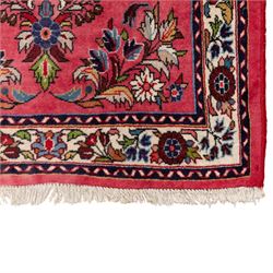 Persian rose ground runner rug, the field decorated with repeating polychrome floral sprays and scrolling palmettes, enclosed by an ivory floral border and narrow navy geometric guard stripes
