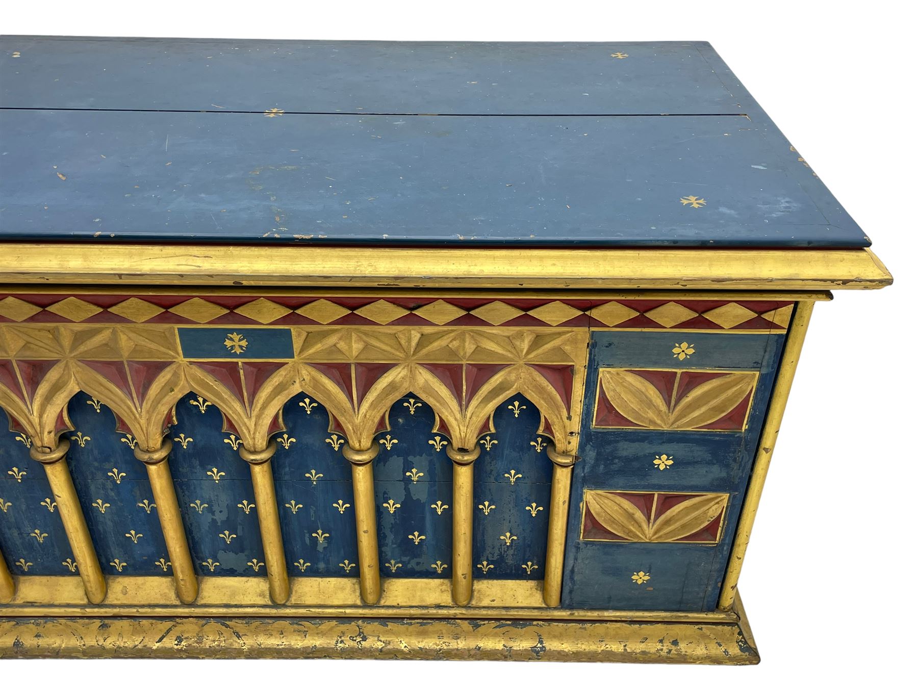 In the manner of William Burges - mid-to-late 19th century English Gothic Revival pine altar or console table, in blue and red paint with water gilding, the moulded rectangular top over six pointed arches with turned column supports, the front carved with a single row of lozenges and incised stylised motifs