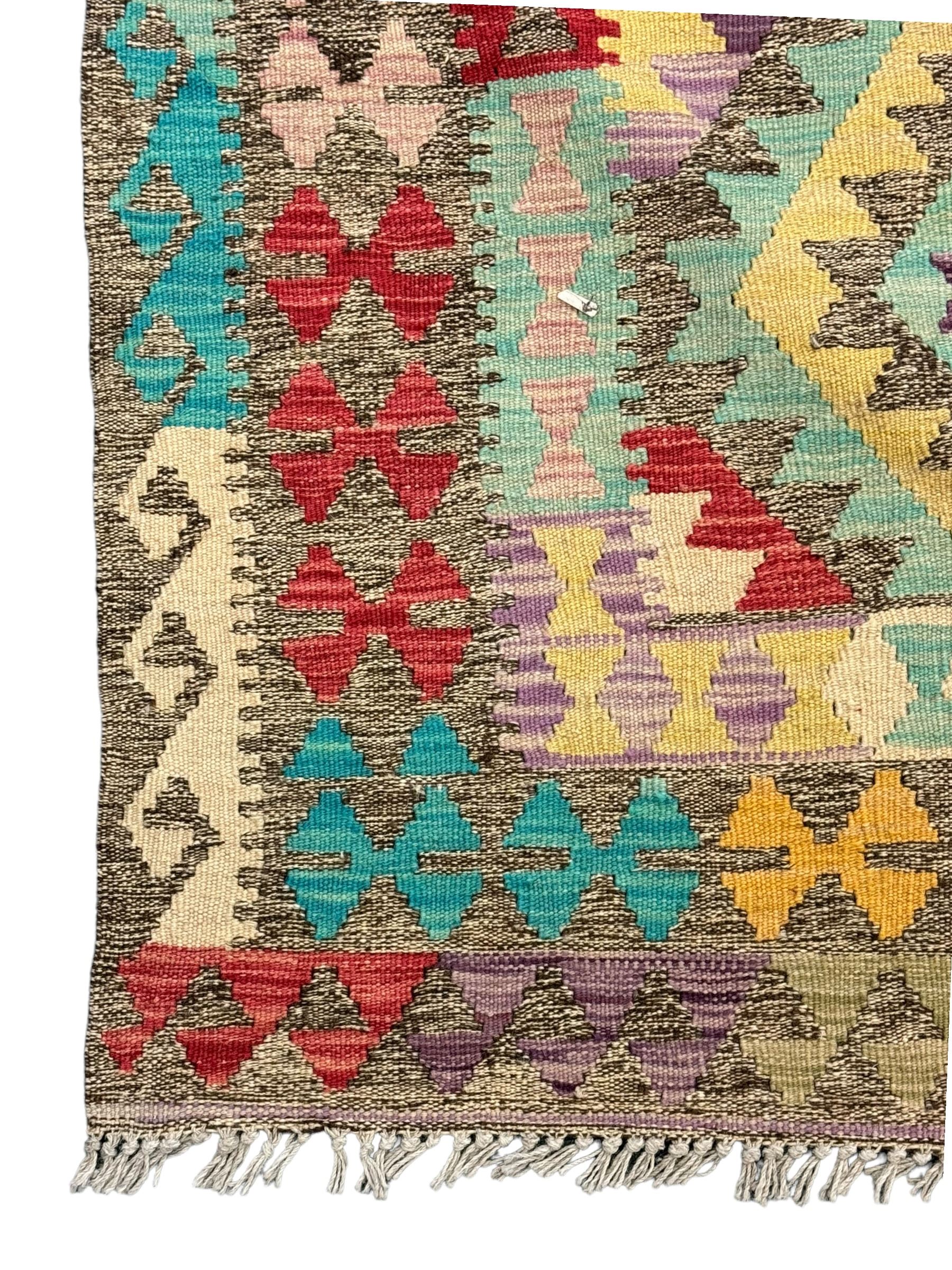 Anatolian Kilim cream ground rug, decorated with repeating diamond motifs in red, blue, yellow, and green, bordered by narrow bands of stylised geometric patterns in contrasting shades