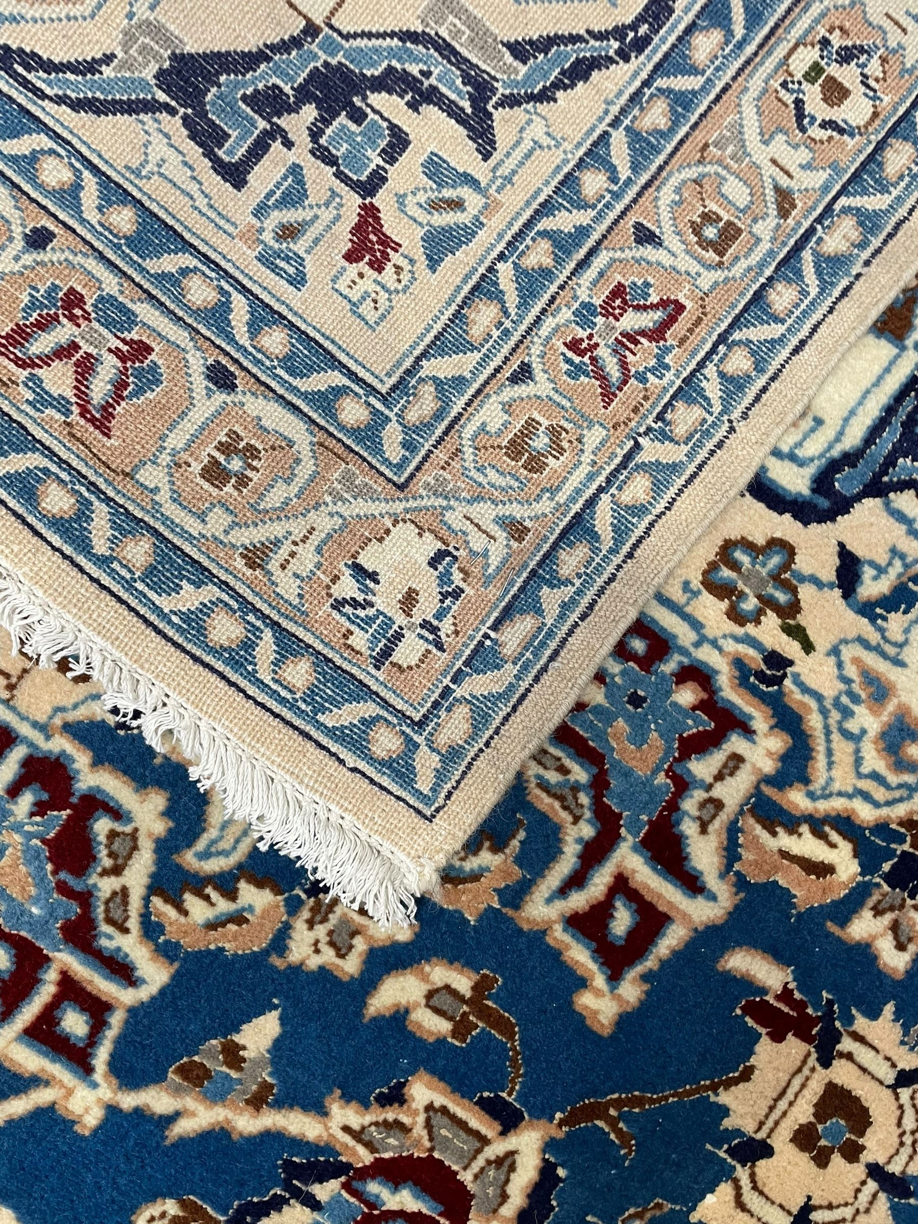 Persian Kashan blue ground rug, central floral rosette medallion within a field of swirling branches and palmettes, the border with trailing pattern interspersed with stylised plant motifs