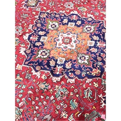 Kashan red ground rug carpet, the field decorated with scrolling stylised foliage with central medallion, repeating blur ground border with flower head guard, 390cm x 295cm