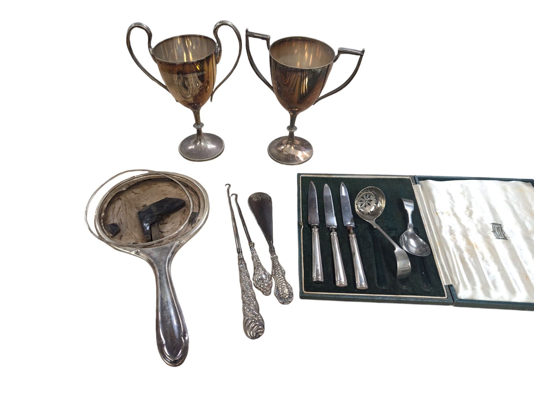 Two silver mounted button hooks and a shoe horn, three silver handled knives, silver hand mirror mount, two silver plated trophies, etc 