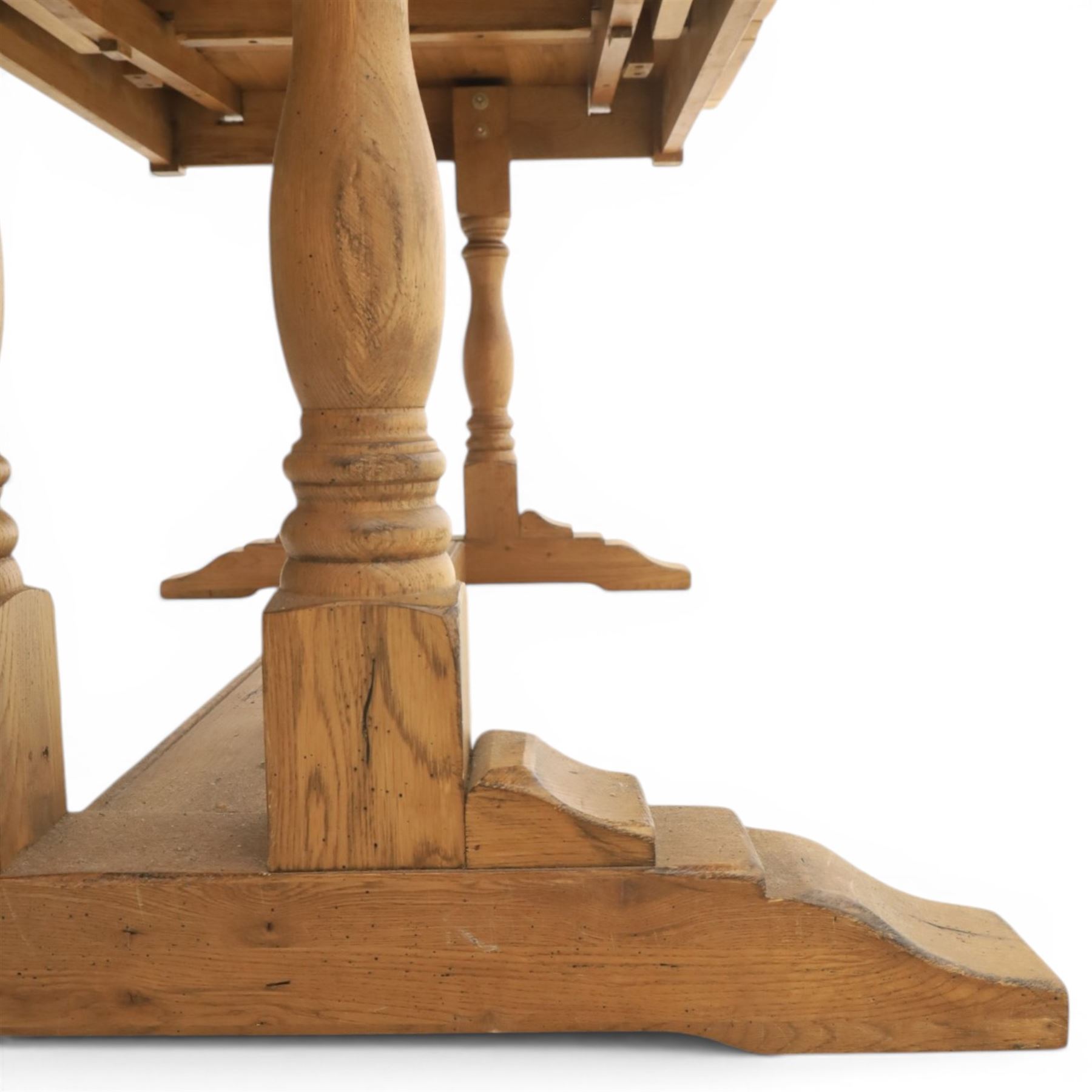 Traditional oak refectory dining table, fitted with draw leaves to either end extending to 257cm, on twin turned and block supports united by a stretcher, terminating in shaped trestle feet