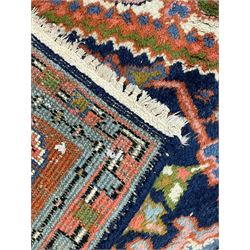 Persian Heriz indigo and rust ground rug, central geometric star medallion decorated with stylised foliate motifs, the border decorated with stylised flower heads