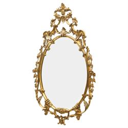 Rococo design giltwood and gesso wall mirror, oval plate within moulded frame, pierced cre...