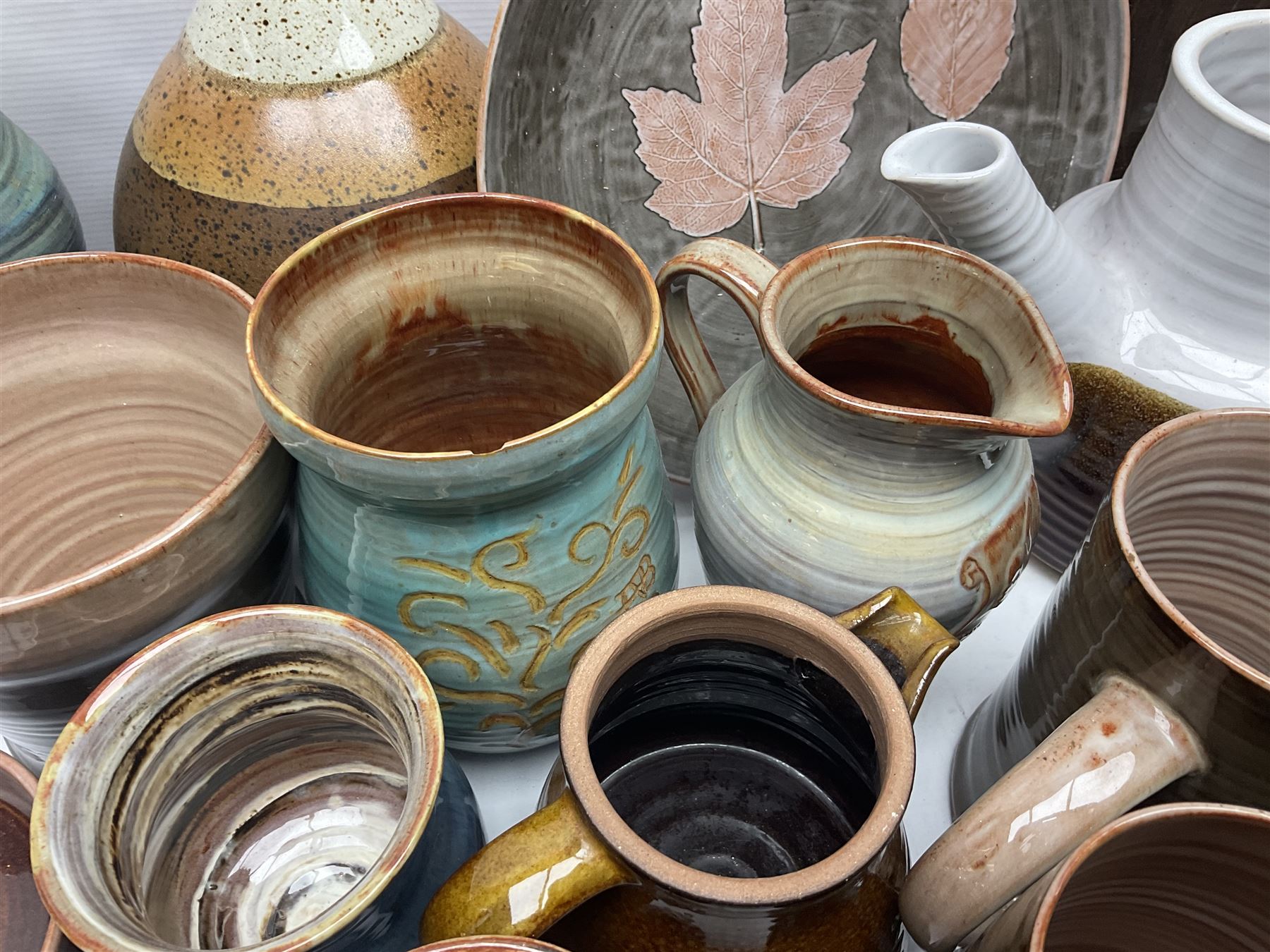 Wold studio pottery tankards, in various colours and relief decoration together with other studio items including vases, jugs and pots 