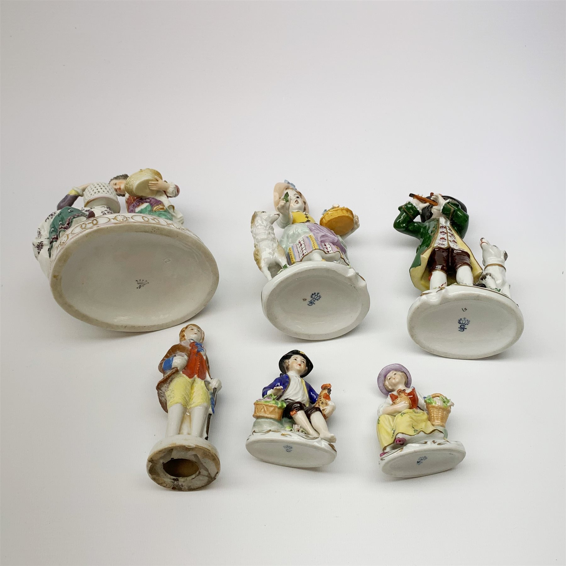 A pair of Sitzendorf porcelain figures, the first modelled as a boy playing the flute, with dog seated at his feet, the second modelled as a girl with basket of flowers and sheep stood beside her, each upon oval gilt detailed base, each with printed mark beneath, H17cm, together with a Naples figure group, a pair of small Sitzendorf figurines, and a later example marked Japan. (6). 