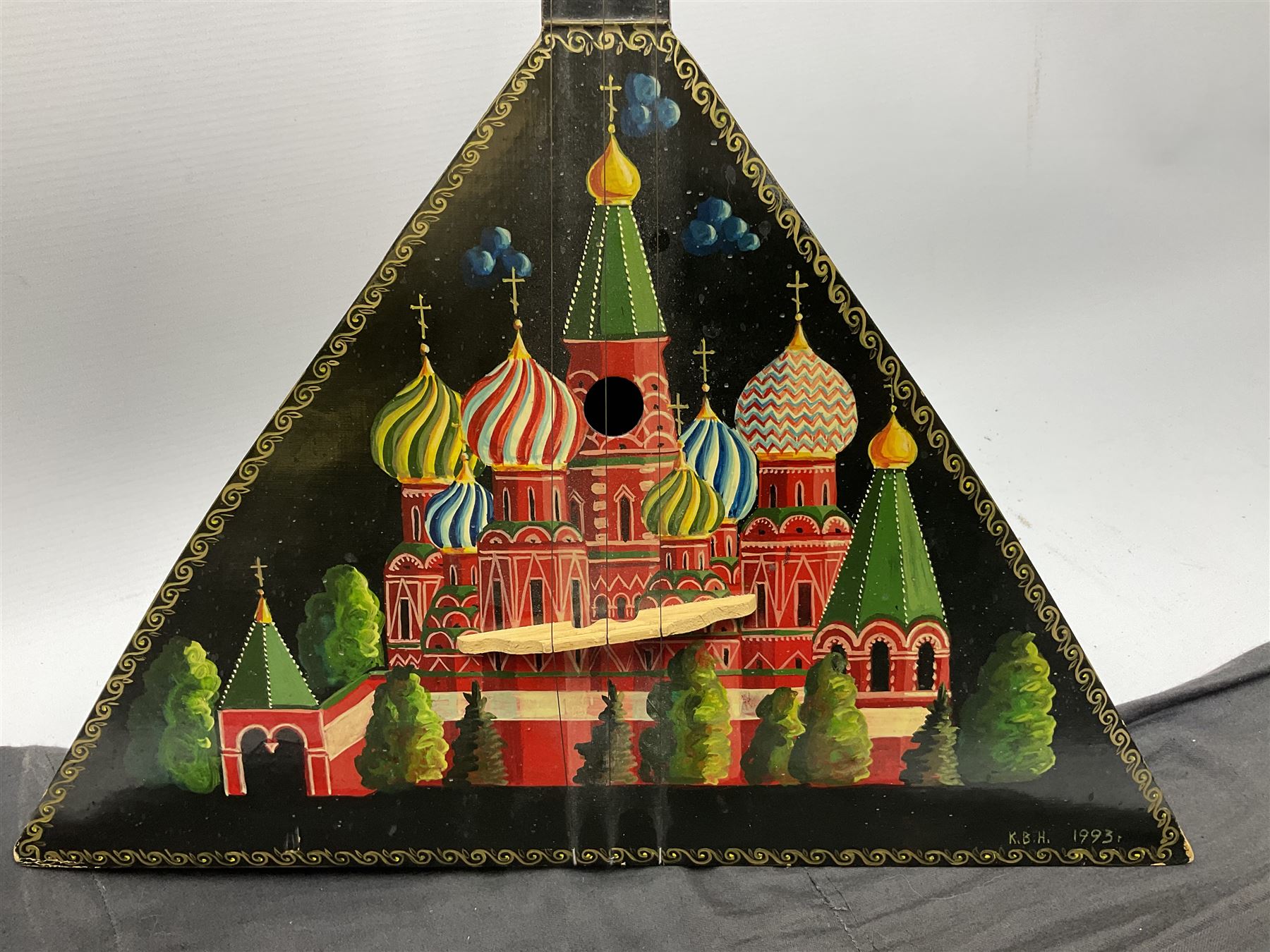 Russian balalaika with six-piece segmented back, the top painted with a scene of Russian onion capped buildings monogrammed K.B.H.1993; bears cyrillic label; L67.5cm; in carrying bag