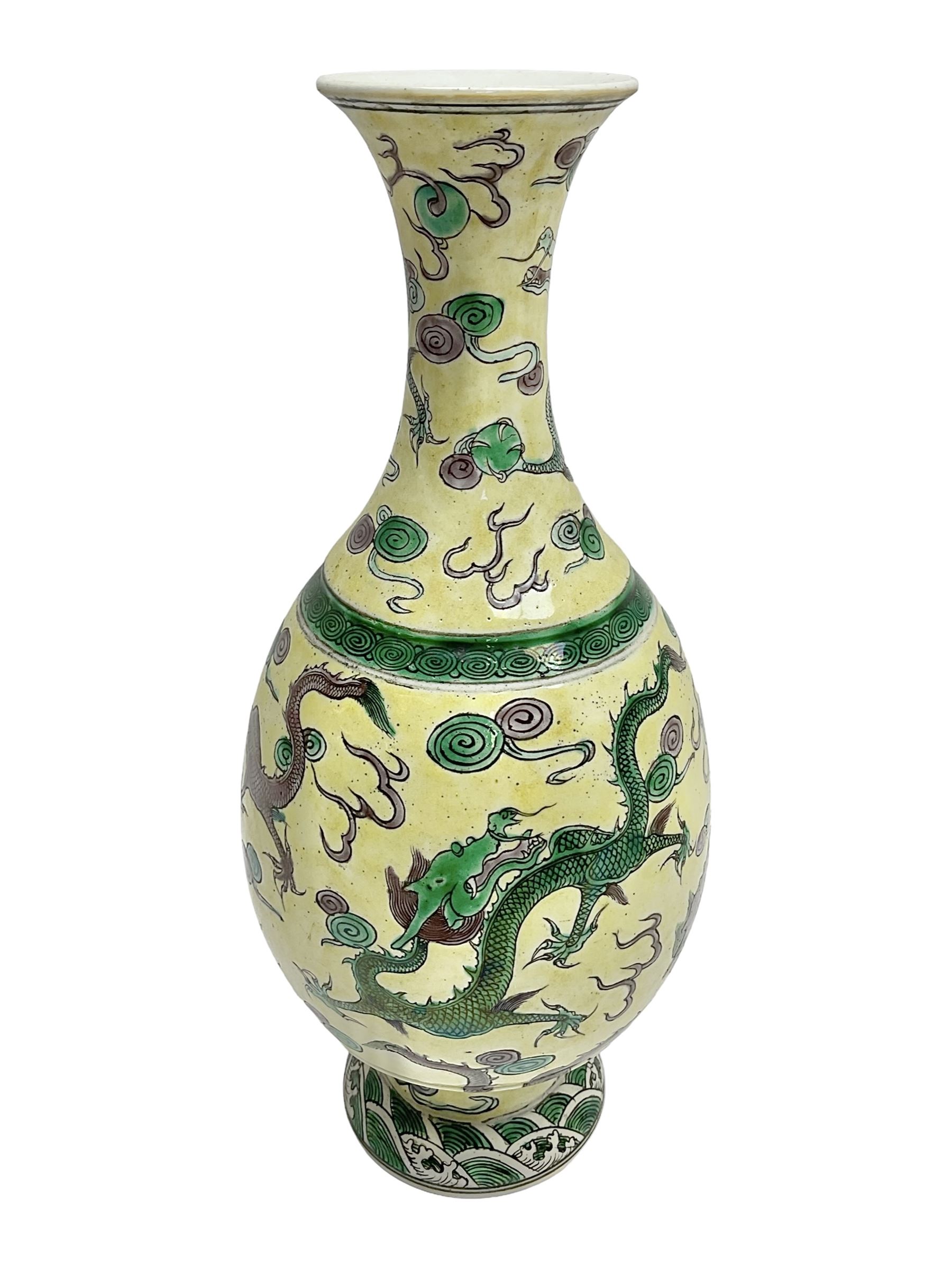 20th century Chinese Famille Verte vase, of slender ovoid form with tapering neck and flared rim, decorated with green and grey enamel with dragons chasing flaming pearls amongst auspicious clouds upon a yellow ground, H30cm