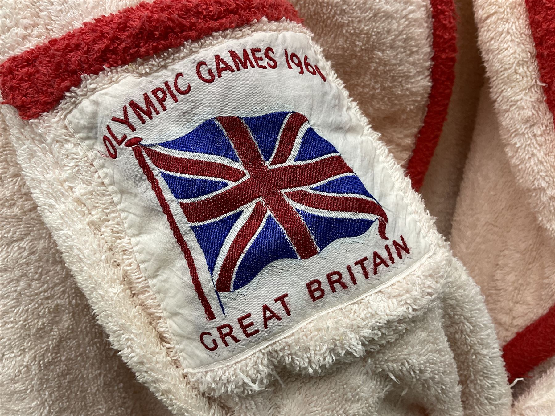 On the direct instructions of Anita Porter nee Lonsbrough Great British Olympic and Commonwealth Games gold medal winning swimmer - collection of early and international memorabilia comprising original Huddersfield Bath Club track suit top bearing eight stitched on cloth badges including British Empire & Commonwealth Games 1958 England Team, YSASA, North Eastern Counties ASA, ESSA Division 3,  English Schools Swimming Association winner etc
The swimming costume Anita wore at the 1958 Commonwealth Games in Cardiff, her first major championships, where she won two gold medals. The grey elastic on the sides, in those days, she would use to make it tighter and more streamlined.
Blue track suit from the 1960 Olympics which she wore on the podium receiving the gold medal.
1960 pool side towelling robe used at the Rome Olympics (interesting to note her name is spelt wrong on the embroidered label).
1962 Commonwealth Games pool side towelling robe used in Perth Australia when winning three Gold medals. 
It was also this year she became BBC Sports Personality of the year, the first female to do so.
Her 'lucky' pool side towel which she took with her to every event she competed in and which can be seen round her neck in many official celebratory photographs. Copies of some of these photographs are included for identification.
In addition there are two souvenir programmes of an evening event to honour Anita at The Theatre Royal Huddersfield and she has kindly signed the front cover on one of these.