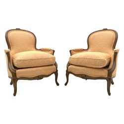 Pair French style beech framed armchairs, the cresting rail carved with flower heads and foliage, sprung seats with loose cushions upholstered in pale pink fabric with raised geometric repeating pattern, shaped arms and cabriole supports carved with scrolls and flowers