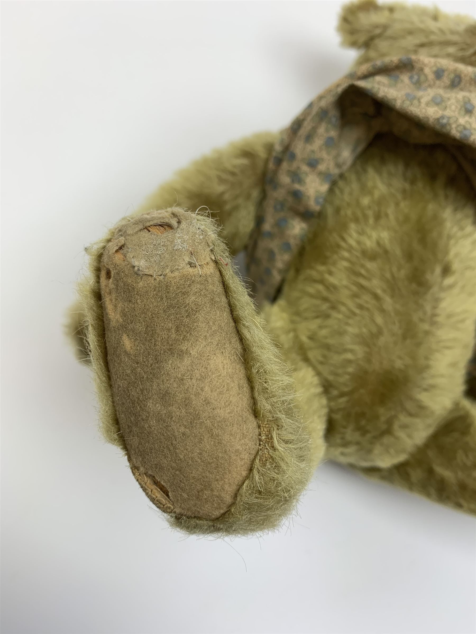 Early 20th century German Steiff teddy bear c1910 with wood wool filled humped back mohair body, swivel jointed head with black boot button eyes and horizontally stitched black nose and mouth, FF metal button to left ear, jointed elongated limbs with felt paw pads and black stitched claws H13