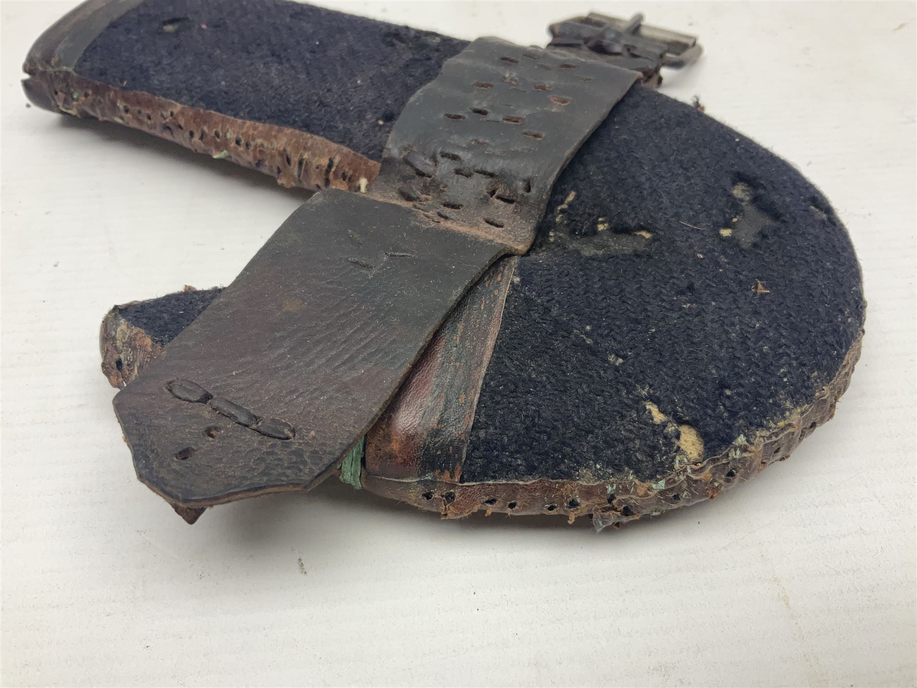 Eastern Jambiya, the 19cm double edge steel blade with raised medial ridge, waisted horn grip with pique work and white metal band; in stitched leather scabbard L33cm overall
