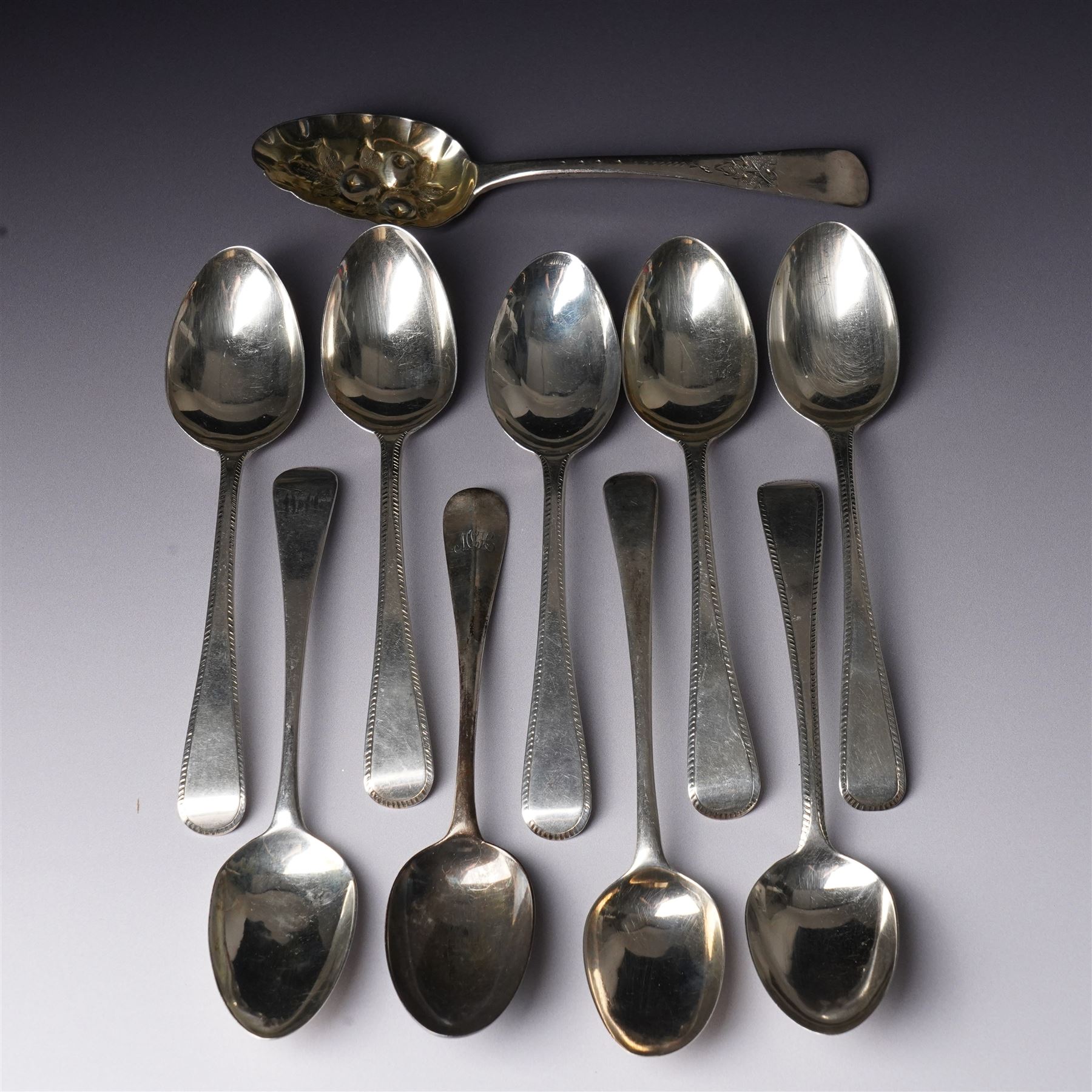Set of six George III silver dessert spoons with bright cut stemsLondon 1818 Maker Thomas Wallis II and Jonathan Hayne, three other silver dessert spoons and a silver berry spoon with gilded bowl (10)