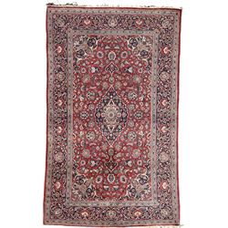 Persian Kashan red ground rug, the field decorated with scrolling foliate and stylised flower heads, floral medallion and spandrels, the main border decorated with scrolling floral design