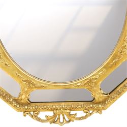 Late 19th century French giltwood and gesso wall hanging cushion mirror, the pierced foliate rocaille pediment extending acanthi C-scrolls and trailing bellflowers, over a floral garland and cartouche moulded rails, the central oval bevelled plate surrounded by further bevelled cushion mirrors, with out-scrolling pierced motifs flanking the floral egg-and-dart moulded outer edge, over a pierced foliate cartouche terminal