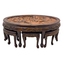 Early 20th century Chinese hardwood nesting coffee table, oval top carved with figures and traditional pagoda scenes with carved frieze, complete with six inset stools or side tables, raised on tapering supports with paw feet