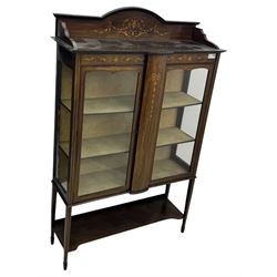 Edwardian mahogany and satinwood crossbanded display cabinet, arched pediment centred by marquetry scrollwork and ribbon decoration, twin glazed doors enclosing a lined a shelved interior, raised on square tapering supports joined by a shaped undertier with diamond parquetry inlay, terminating in spade feet
