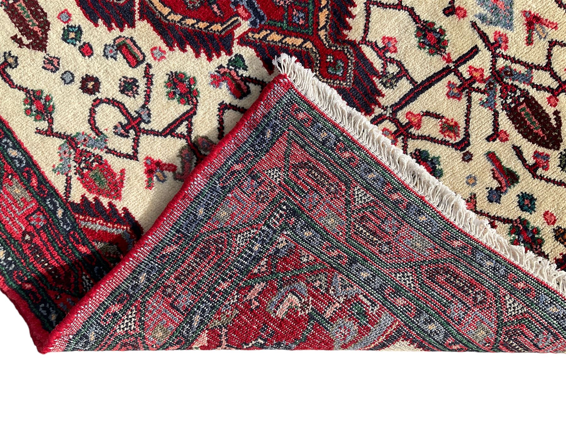 North West Persian Saveh crimson ground runner rug, the three lozenge pole medallions in an ivory field, surrounded by stylised plant motifs, the guarded border decorated with repeating geometric patterns