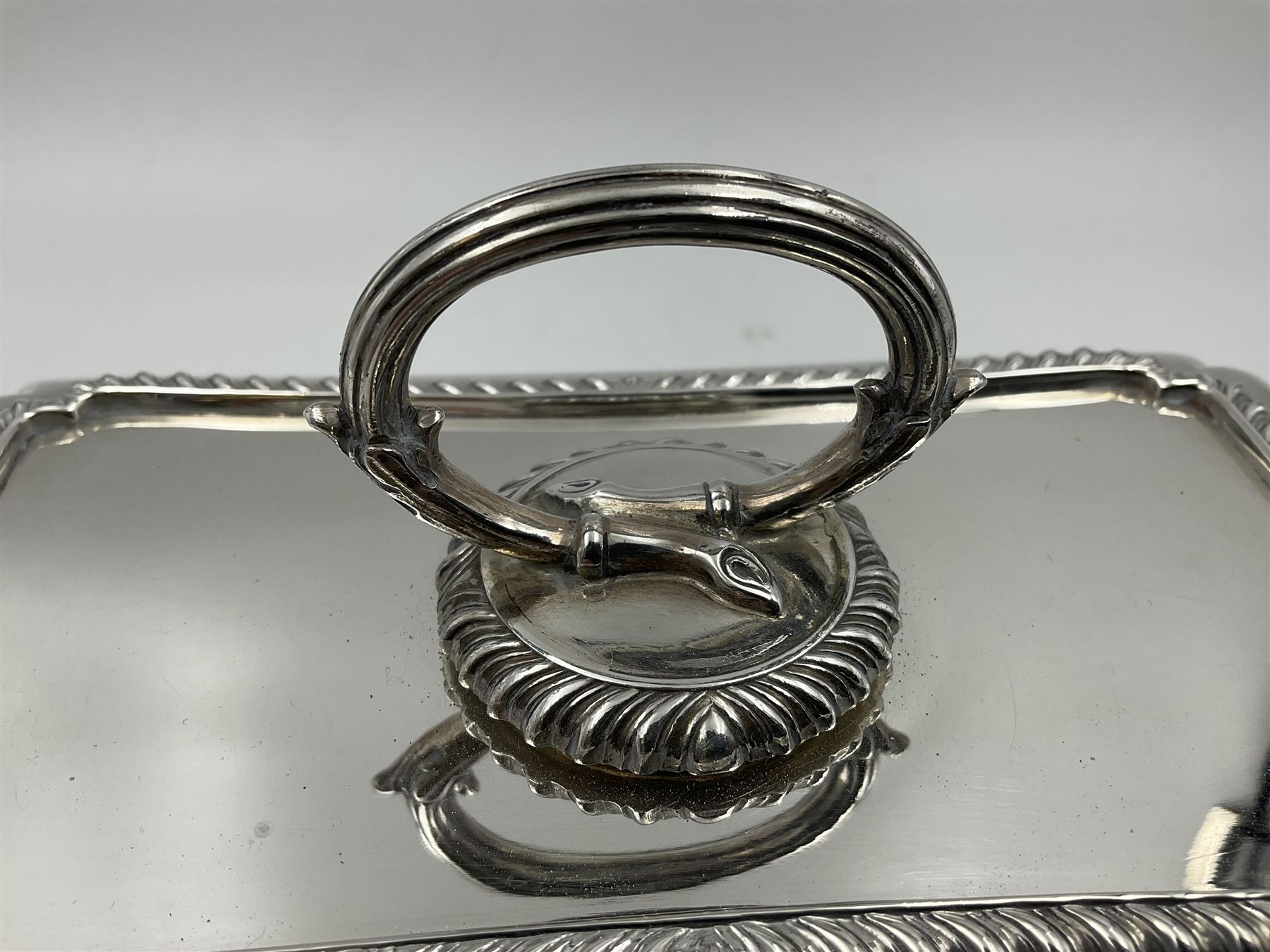 Early 20th century silver entree dish and cover, of rectangular form with shaped corners and oblique gadrooned borders to base and cover, the cover with loop 'bamboo' handle, hallmarked Thomas Bradbury & Sons Ltd, Sheffield 1930, including handle H10.5cm L24.5cm