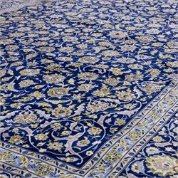 Central Persian Kashan hand-knotted carpet, deep indigo blue field densely decorated with all-over vine, palmette and flowering sprays arranged in a symmetrical pattern enclosed by broad navy border of stylized palmettes, and foliate vine decoration between multiple guard stripes, with cotton fringe ends 