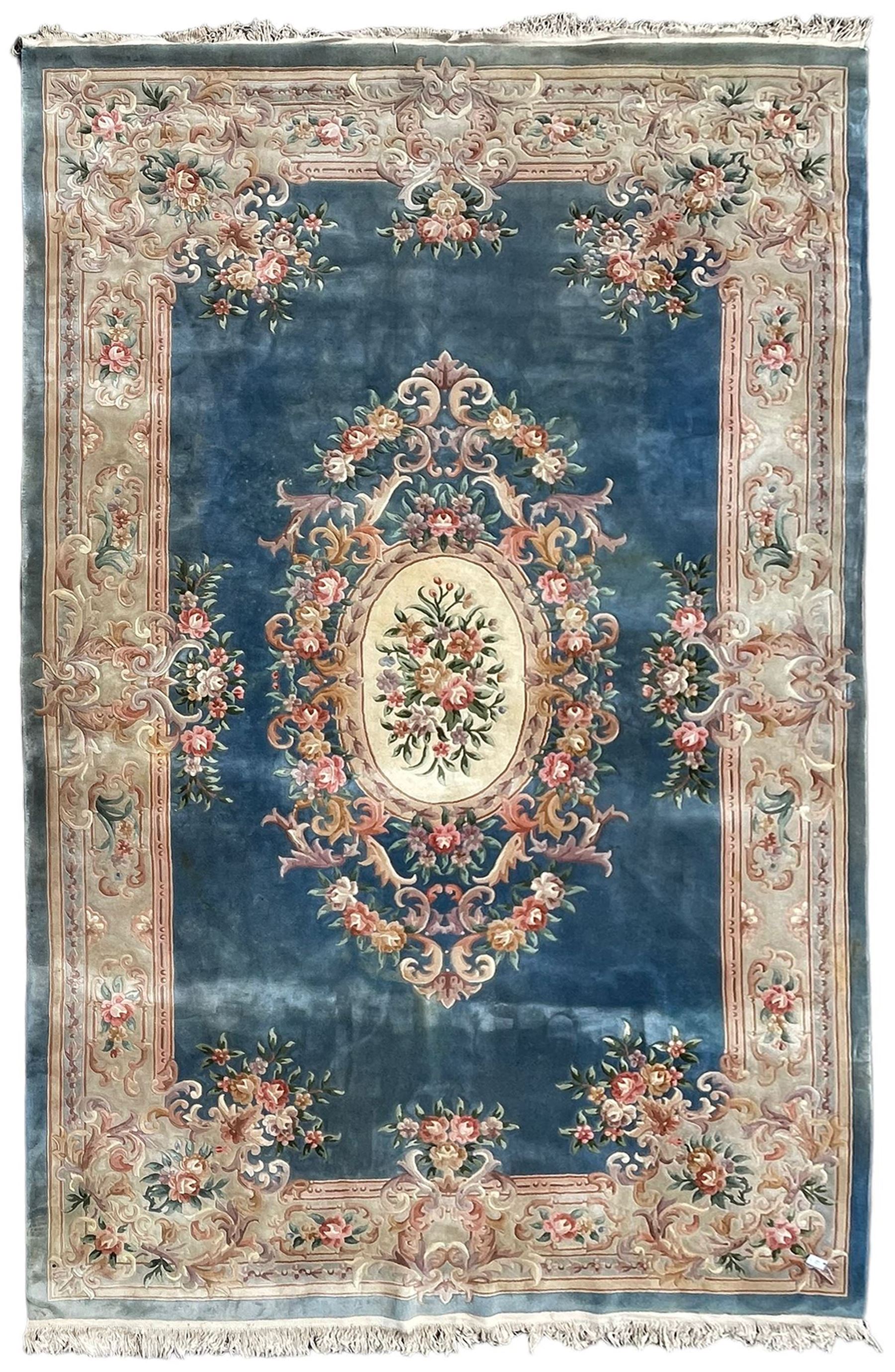 Large Chinese blue ground woollen carpet, overall floral design, central oval medallion surrounded by scrolling floral decoration, wide border with decorated with floral bouquets 