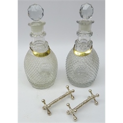  Pair matching Georgian hobnail cut decanters, ovoid form body, double cut neck-rings, central oval cartouche panel, one inscribed D the other vacant with late gilt metal labels 'Anisette' and 'Rhum' and two Victorian silver-plated knife rests   