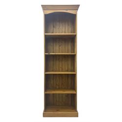 Early 20th century pine bookcase, projecting cornice over arched open shelving area with f...