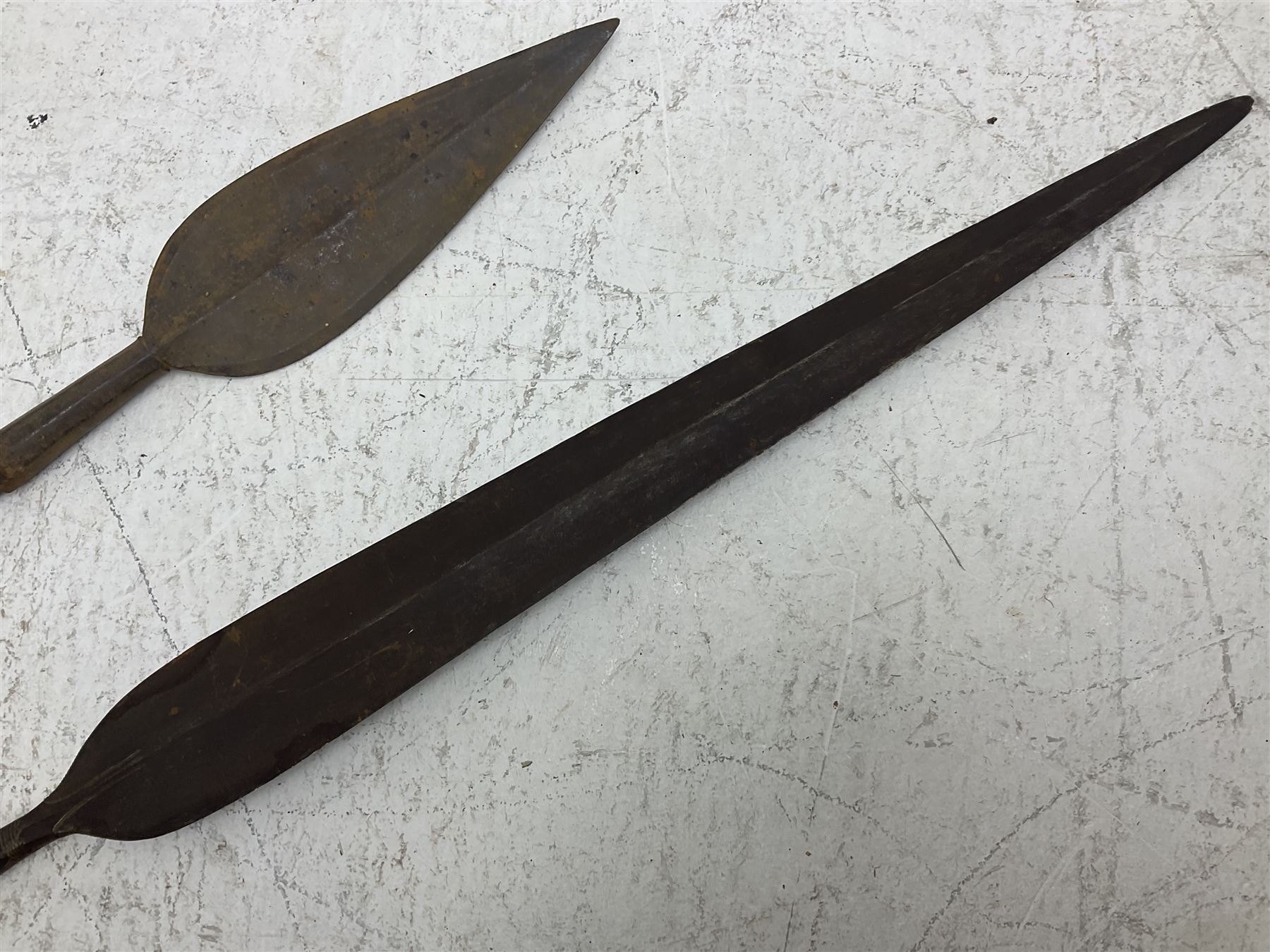 Native long-shafted spear, the large iron head with central medial ridge and decorative neck, on plain circular haft L260cm; and another similar Native long-shafted spear with cane haft L249cm (2)