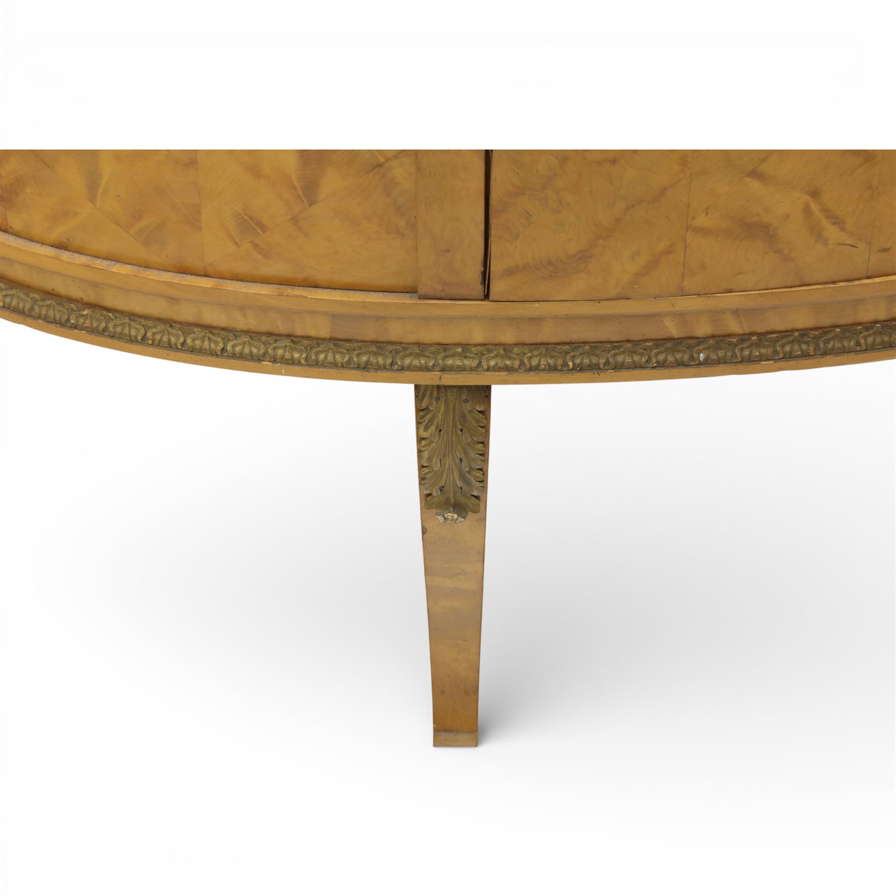Edwardian satin walnut display cabinet, bowed oval form with moulded and dentil cornice over glazed panels, enclosing a laurel wreath damask interior with adjustable glass shelves, the frame applied with gilt metal bead mouldings and mask mounts, enclosing a shelved interior, raised on cabriole supports with moulded feet