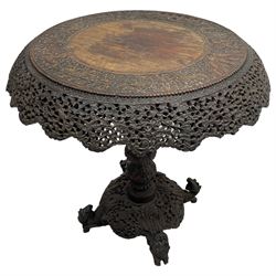 Late 19th century Anglo-Indian carved hardwood occasional table, circular tilt-top carved profusely with mythical animals and foliage decoration, pierced and carved with interlaced leafy branches, leaf carved pedestal supports on a raised platform with further carved and pierced foliage decoration, four carved feet in the form of mythical beasts with gaping jaws 