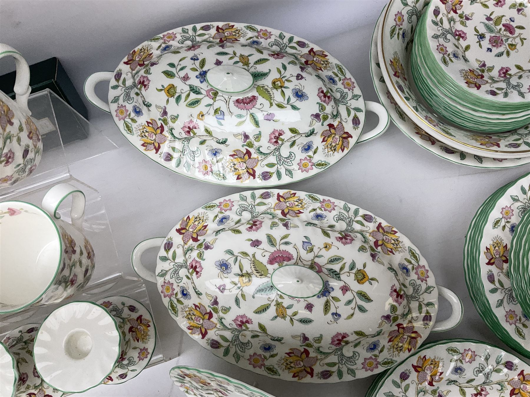 Minton Haddon Hall pattern tea and dinner wares, including basket dish, two covered tureens, six dinner plates, eight dessert plates, twelve tea plates, six soup bowls, six cereal bowls, teapot, coffee pot, milk jug, covered sucrier twelve tea cups and saucers, six mugs, footed bon bon dish, pair of candlestick holders, cake knife and slice etc (81)