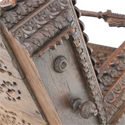 20th century Indian carved hardwood corner shelf, the tiered pagoda form with pierced and carved foliate panels centred by figural carving, supported by turned and carved columns, with shaped brackets and pendant finials