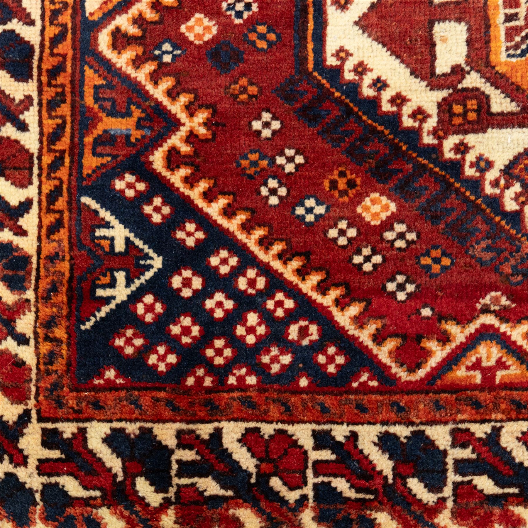 South West Persian Cori hand-knotted rug, red field with three central stepped lozenge medallions enclosing stylized geometric motifs surrounded by scattered rosette devices and angular ornaments within multiple geometric borders, with fringe ends  