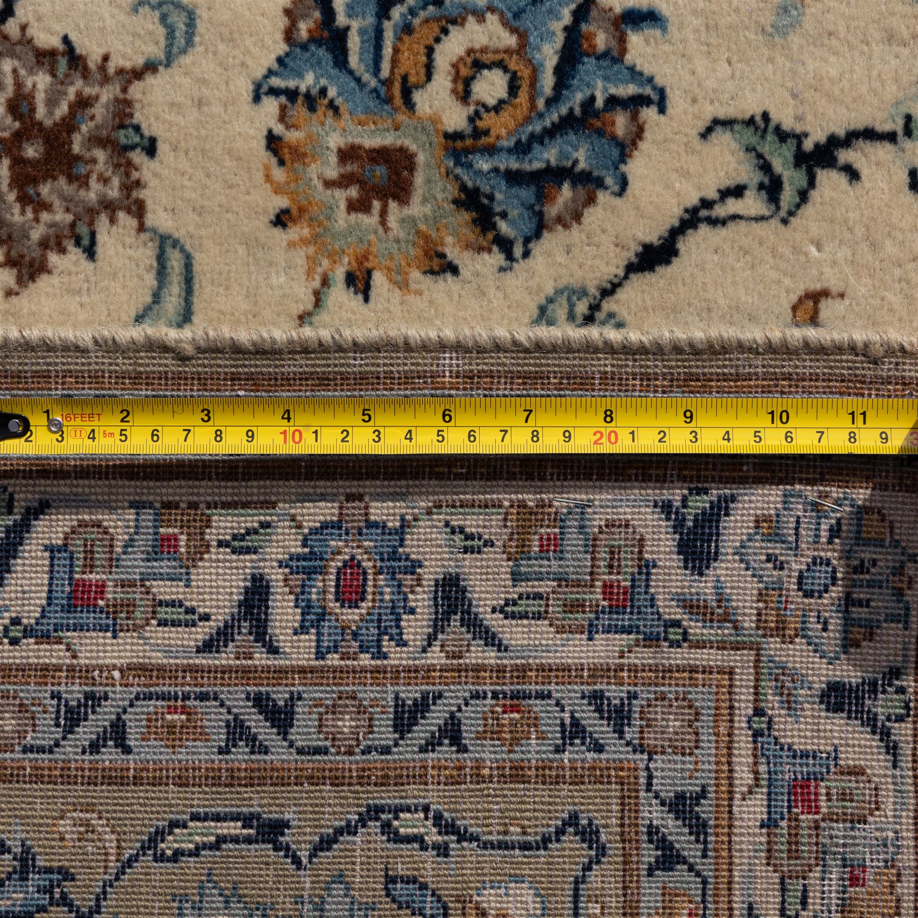 Large Central Persian Kashan hand-knotted carpet, ivory field with small central floral medallion issuing an all-over design of palmettes, rosettes, and scrolling vines enclosed by a complimentary foliate border framed by guard stripes, in a palette of ivory, power blues, and muted polychrome tones, with cotton fringe ends 