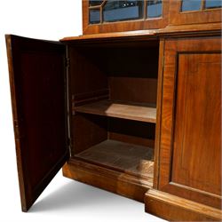 Fine Regency mahogany breakfront library bookcase, the stepped and moulded cornice over four astragal glazed doors enclosing adjustable shelves, the projecting central lower section with a pair of panelled doors enclosing three graduated drawers with brass inset handles above two deep zinc-lined cellarette compartments, flanked by panelled cupboard doors enclosing shelves, the figured mahogany fronts with ebony line inlay, on moulded plinth bases
