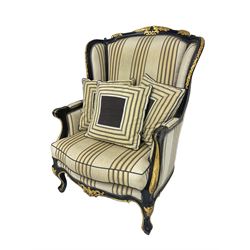 Thomas Messel - Georgian style ebonised and gilt wingback armchair, upholstered in striped fabric, on cabriole front feet