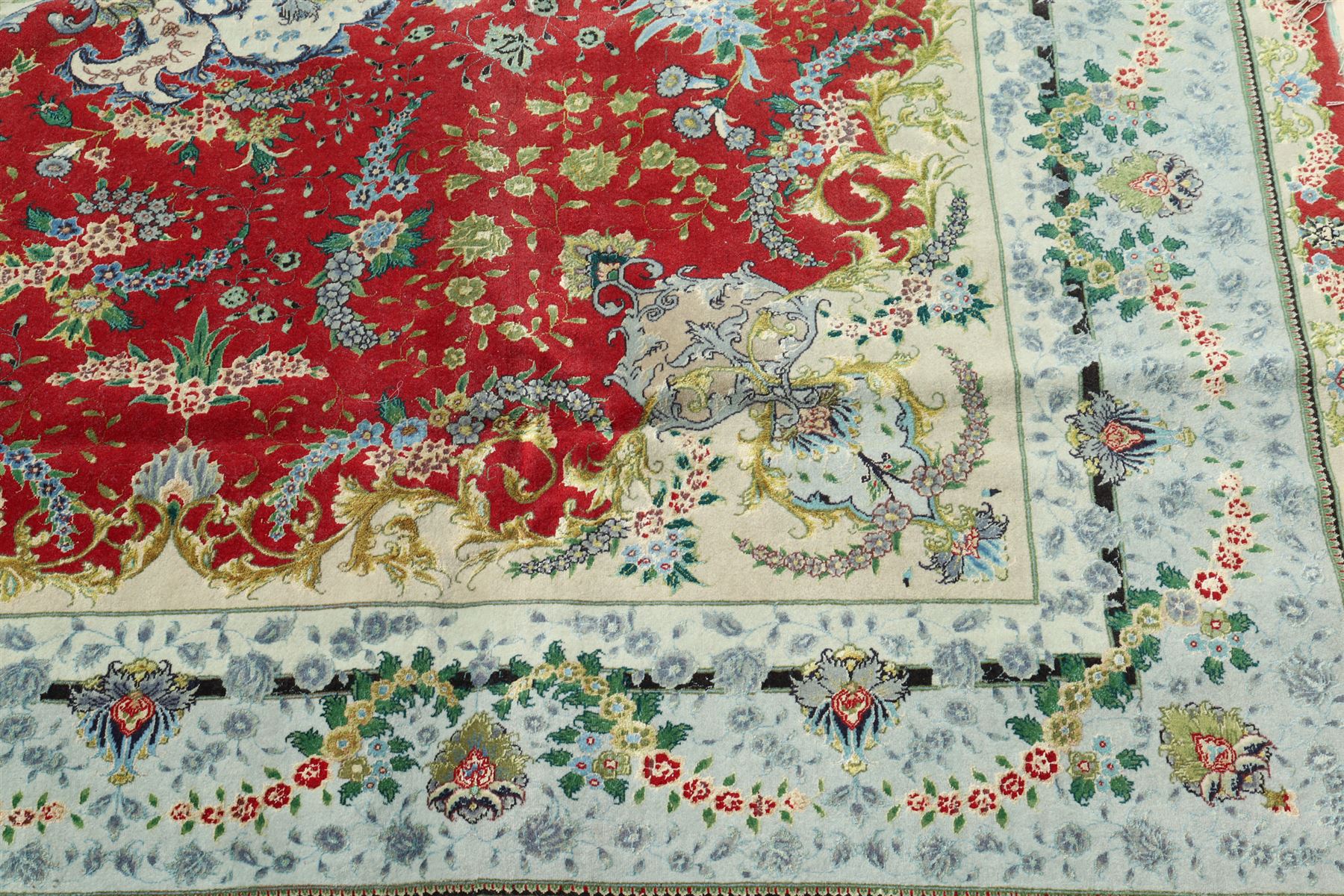 Persian silk inlaid crimson ground Kashan rug, the central shaped field with a floral pole medallion surrounded by trailing floral motifs and festoons of flowerheads, the wide cyan guard line with repeating palmettes and scrolling floral vines