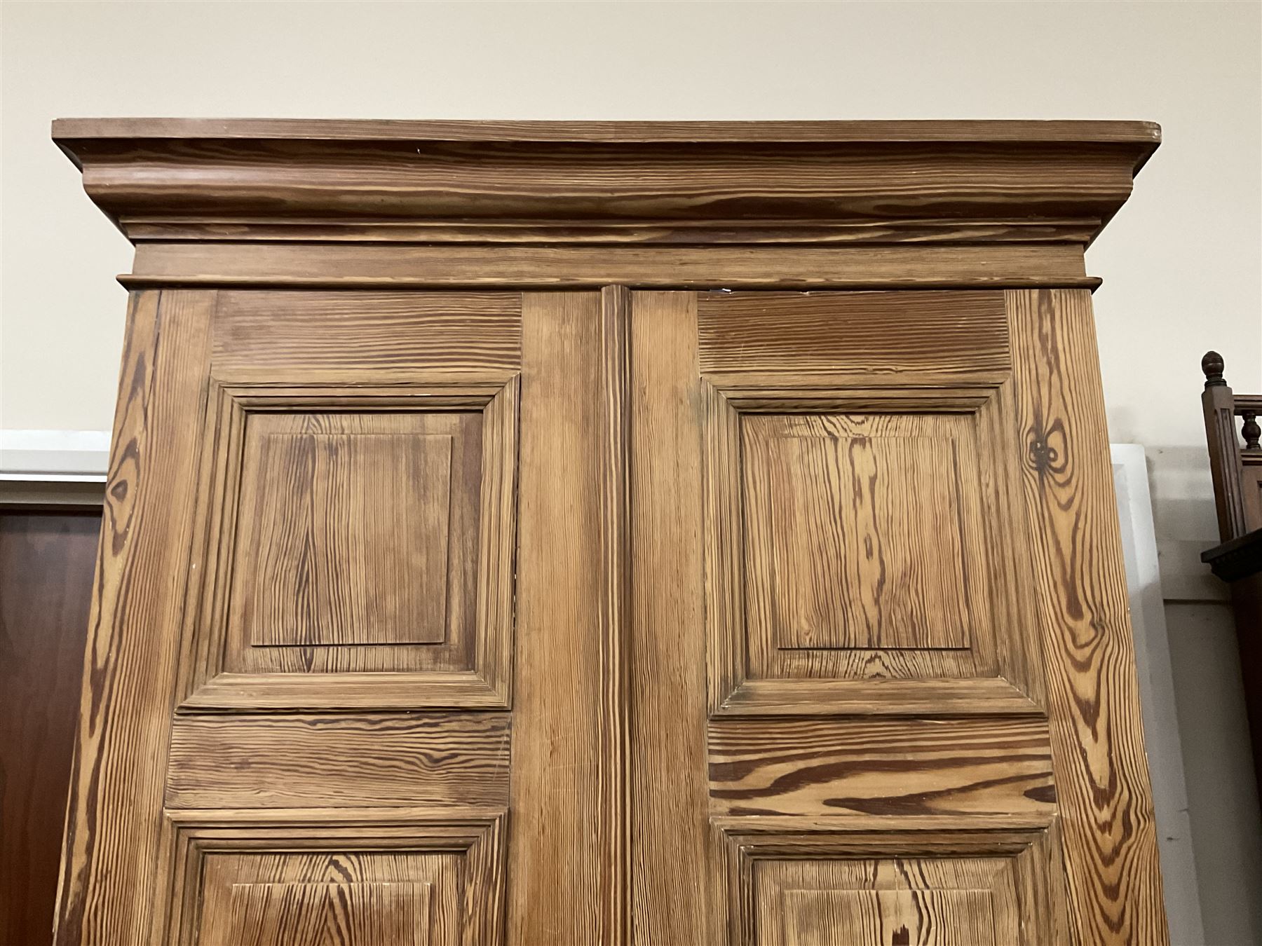 Victorian pitch pine double wardrobe, projecting moulded cornice over two panelled doors, the interior fitted with hanging rail and hooks, single drawer to base