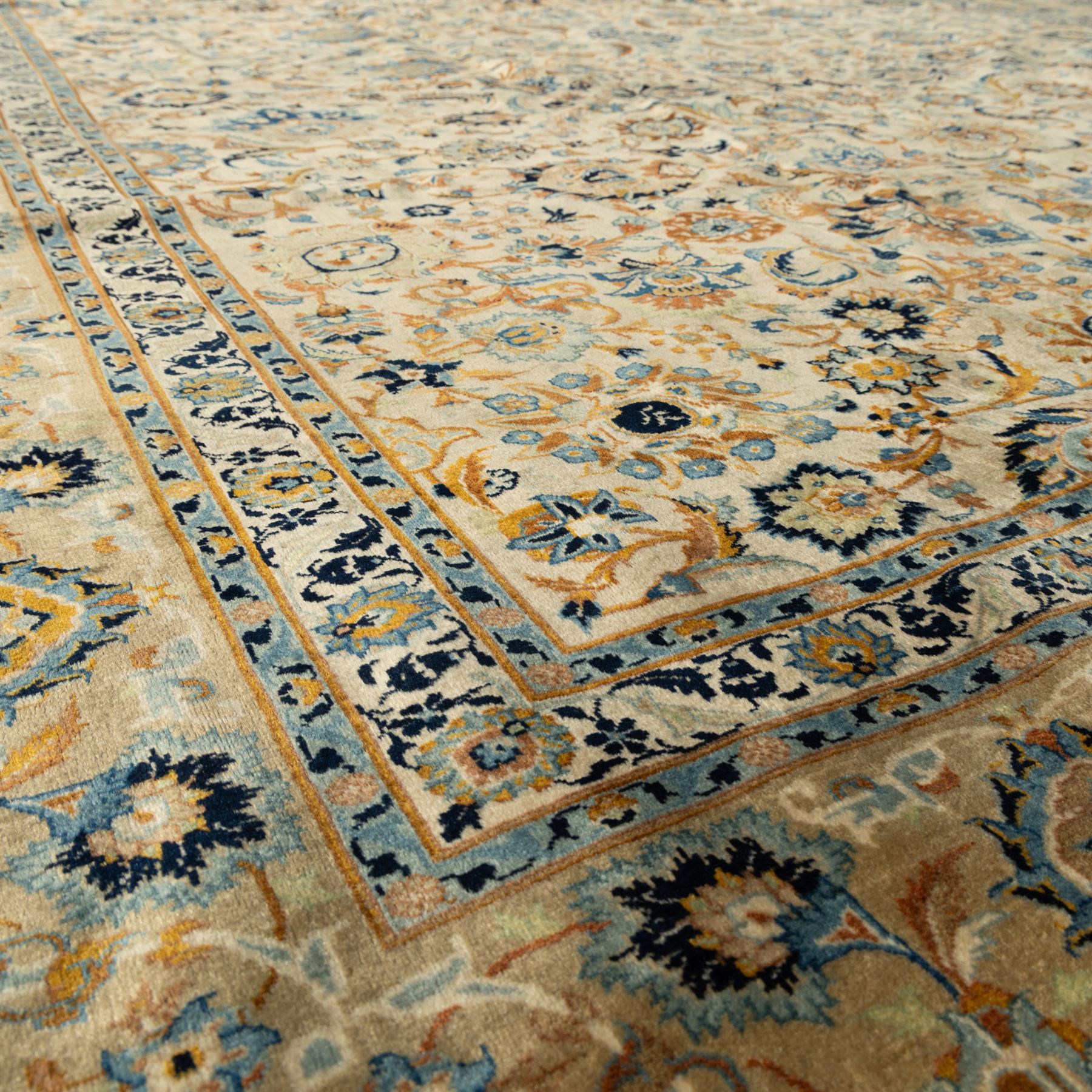 Central Persian Kashan rug, cream ground densely decorated with interconnected floral stems, rosettes and palmettes in shades of blue and gold, framed by layered foliate borders, woven in the Kashan region of Iran