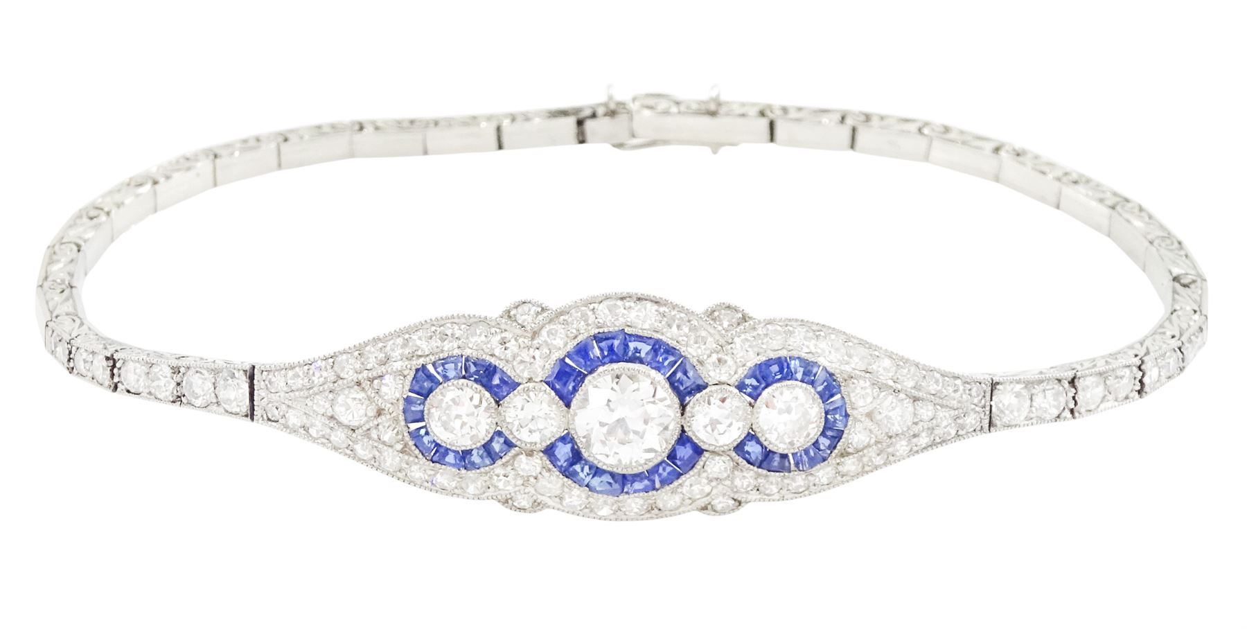 Art Deco platinum diamond and sapphire target design bracelet, five old cut diamonds, surrounded by calibre cut sapphires and old cut diamonds, all milgrain set, to a graduating old cut diamond and polished articulated rectangular link bracelet, the sides with engraved foliate decoration, French import mark, principal diamond approx 0.45 carat