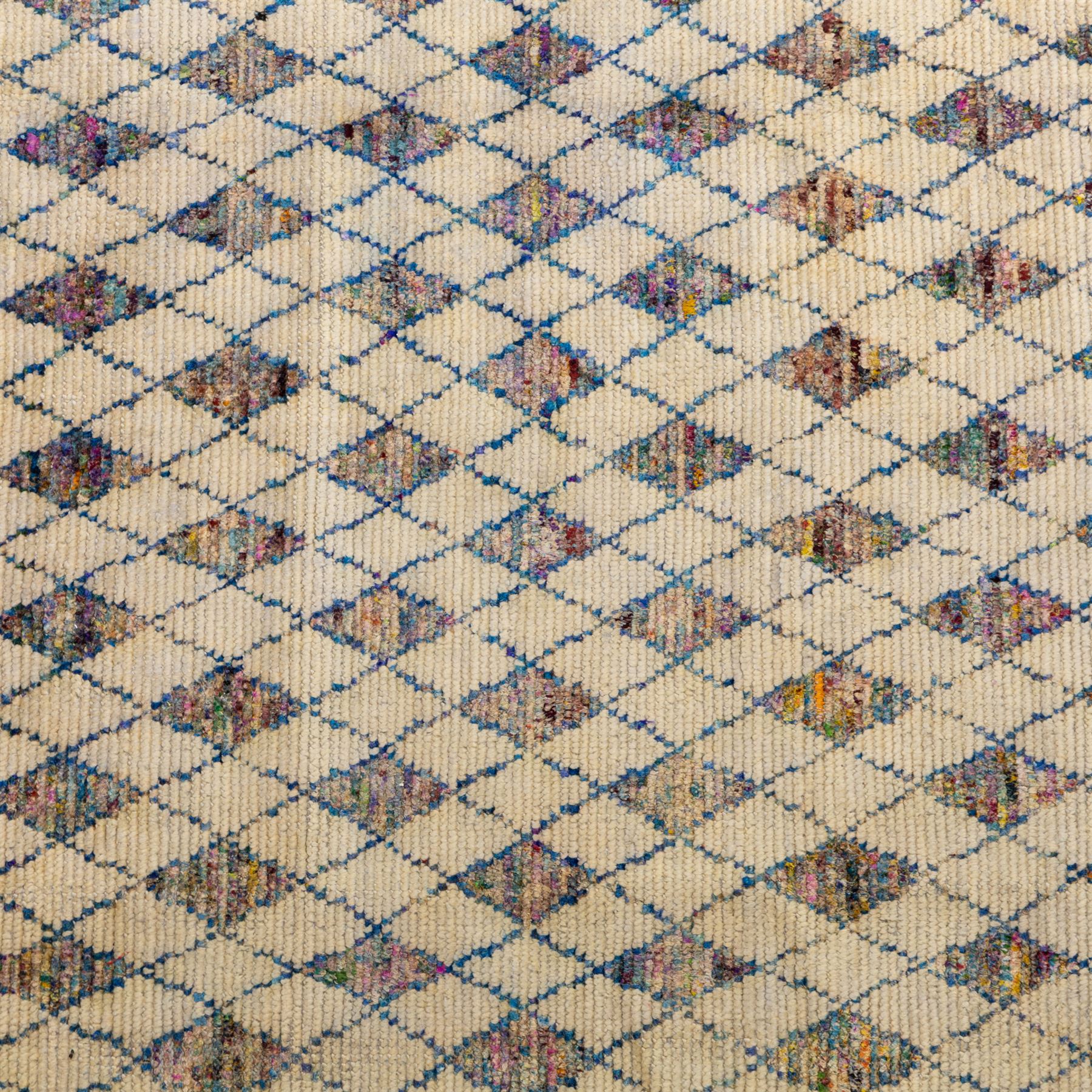 Contemporary Moroccan Berber design wool rug, cream field with blue diamond lattice, decorated with repeating multicoloured lozenge motifs, short fringe ends and bound sides