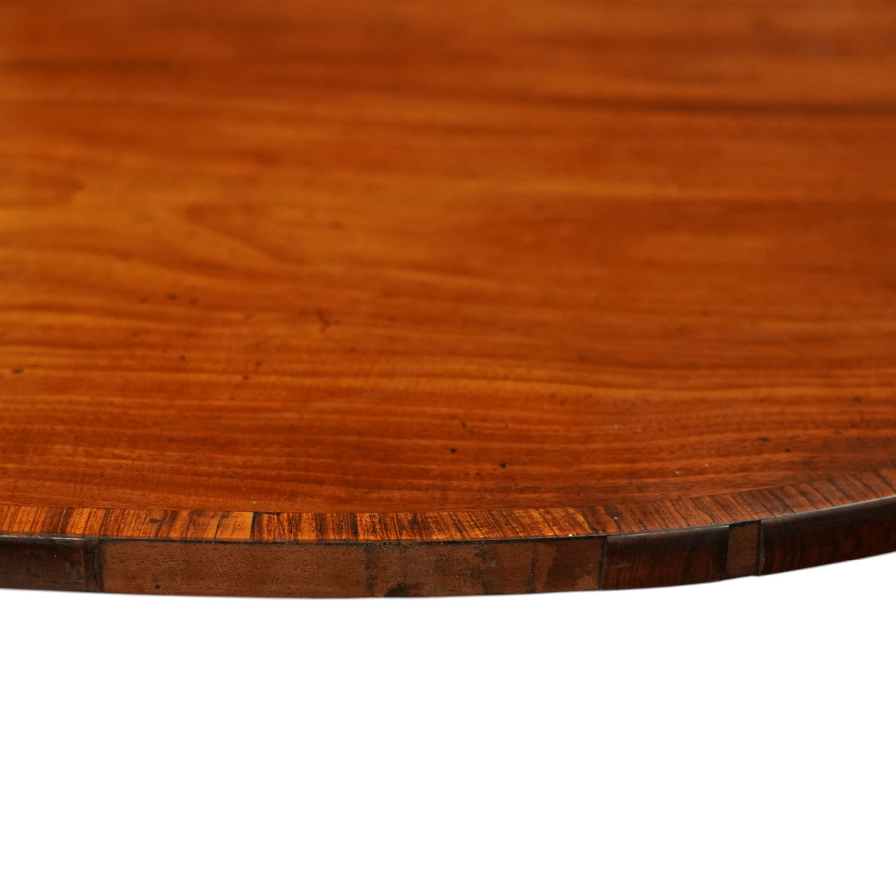 Regency figured mahogany breakfast table, figured rectangular tilt-top with rounded corners and rosewood banding, on turned column with four out-splayed supports with brass cups and castors 
