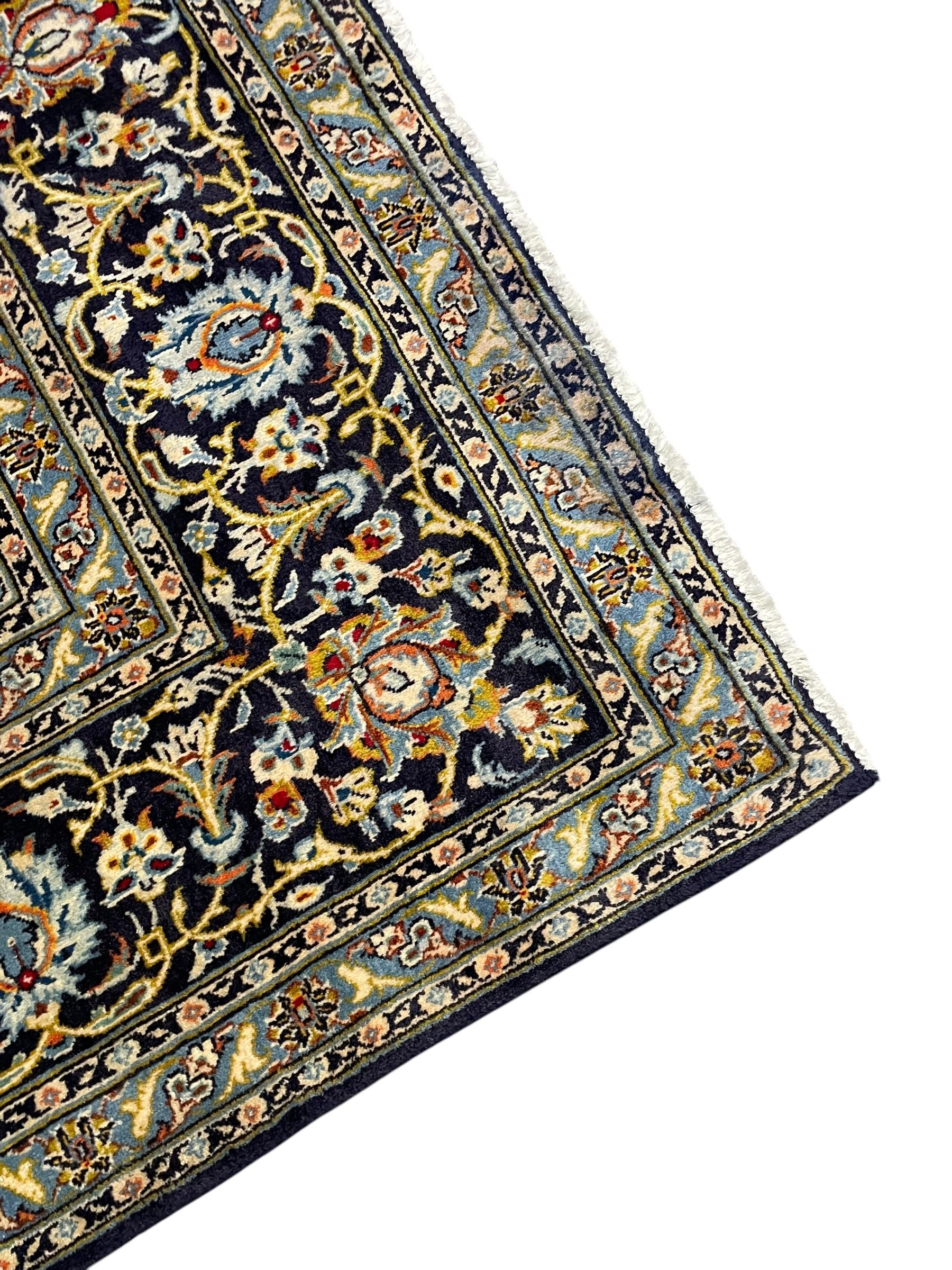 Persian Kashan indigo ground carpet, floral pattern light blue ground central medallion and spandrels, the fielding decorated with interlacing leafy branches and palmettes, the repeating floral pattern border enclosed within guard stripes