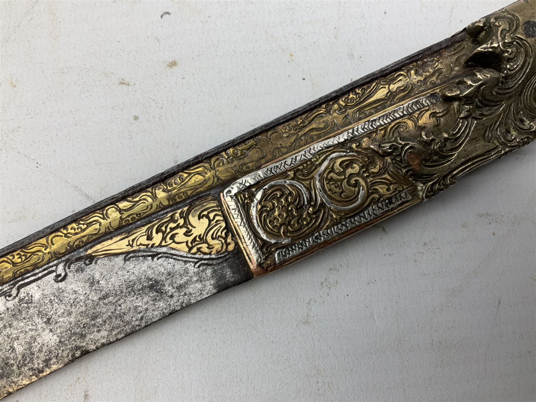 19th century Singhalese knife pia kaetta, the 20cm steel blade inset with yellow and white metal, with metal mounted carved pistol grip, in plain wooden scabbard L33cm overall